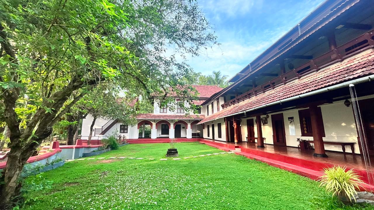 The central courtyard of The Heritage 1866 Judge Bungalow, with its lawn, red oxide verandah and tiled wooden wings on two sides